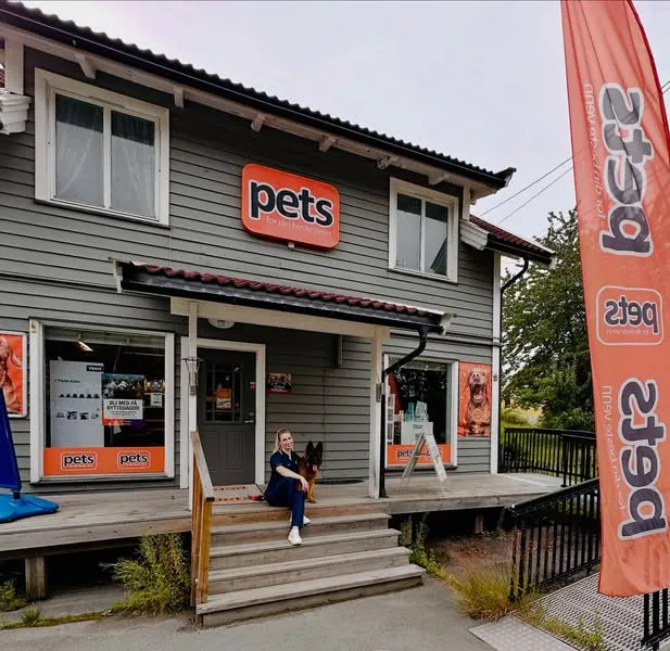 Vita sitter på trappa foran Pets-butikken i Røykenveien 143 sammen med schäferen Freja. Over inngangen henger Pets-skiltet.